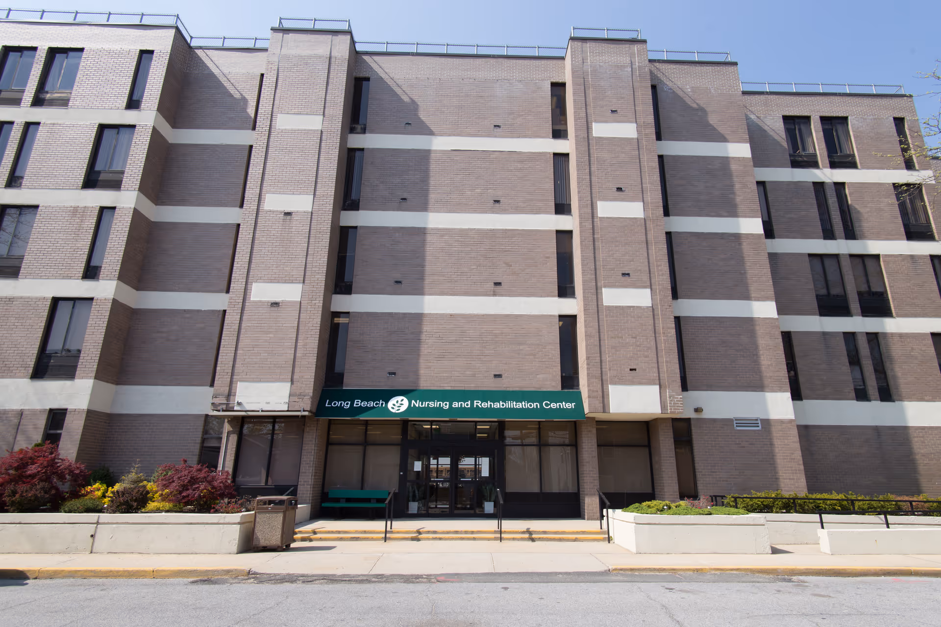 Front view of a brick nursing and rehabilitation center with a green sign.