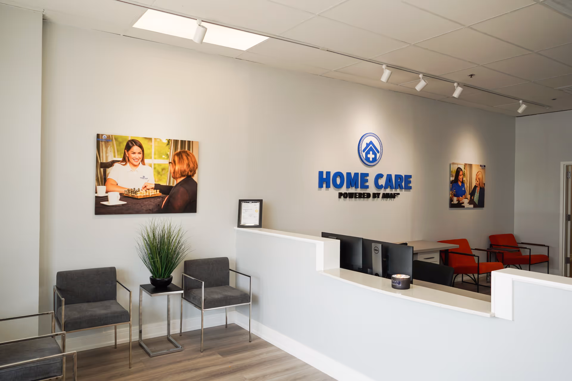 Reception area with desk, seating, and Home Care Powered by AUAF sign.