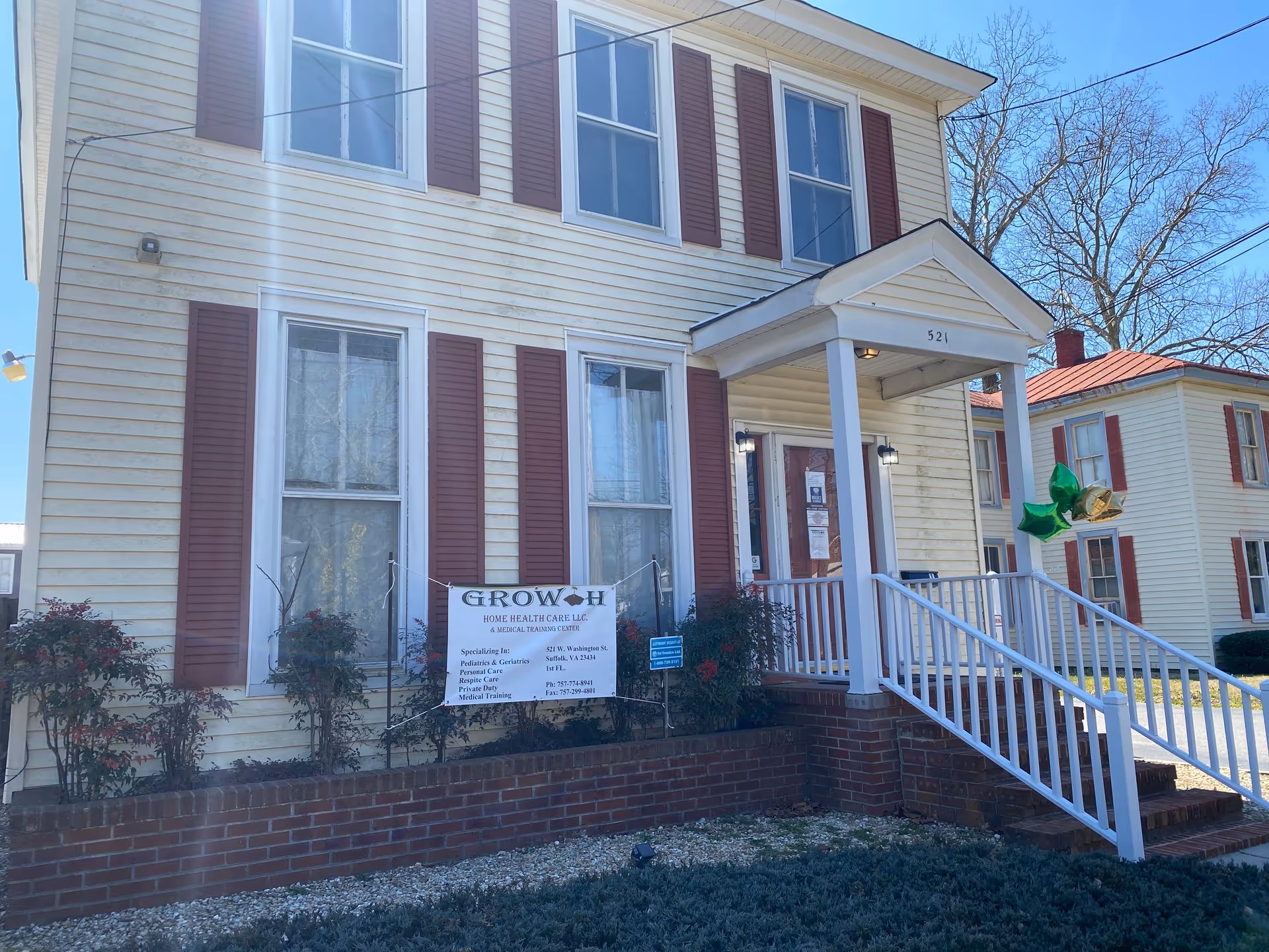 Two-story cream-colored building with maroon shutters, front porch, and Growth Home Health Care LLC sign.