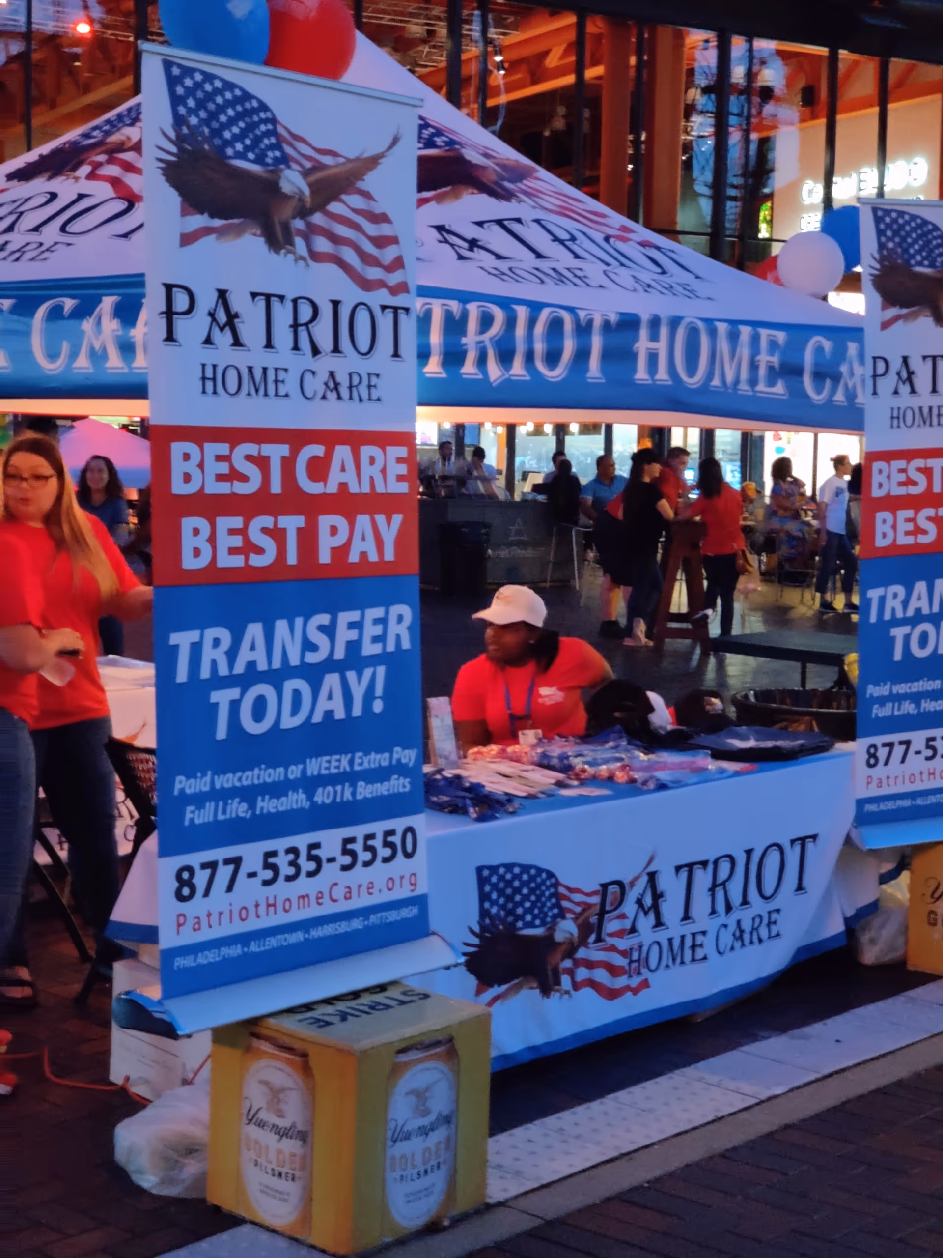 Promotional Patriot Home Care booth at an outdoor event with banners and staff.