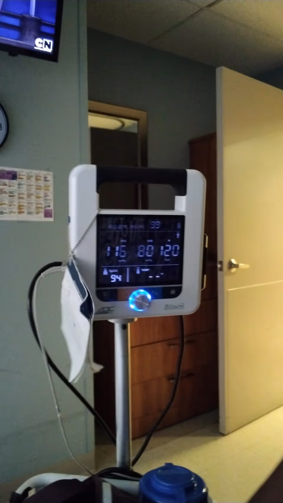 Vital signs monitor on a wheeled stand in an interior room.
