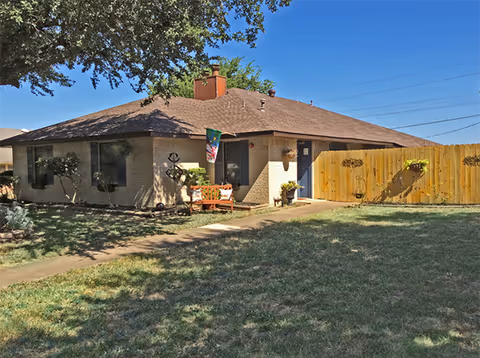 Single-story RCFE building with brick exterior, front lawn and wooden fence.