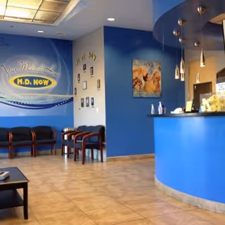 Blue-walled lobby with curved reception desk, seating chairs, and wall artwork.