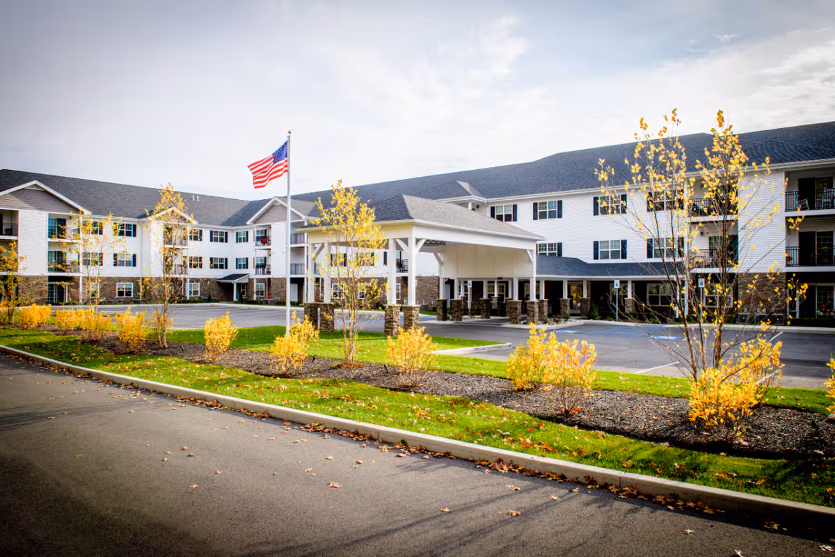 Front exterior of Summit at Saratoga senior living facility with flag and landscaped shrubs
