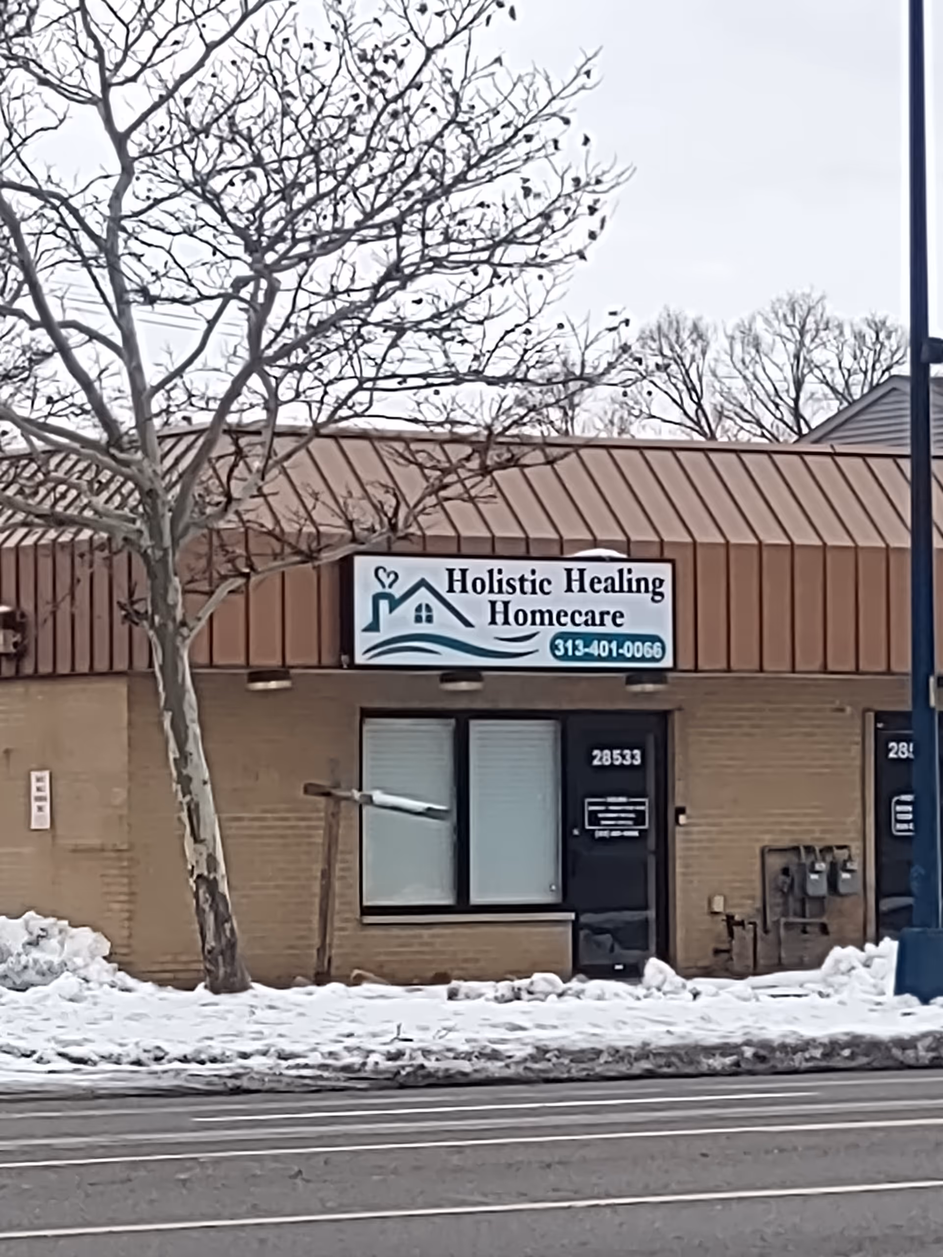 Exterior of Holistic Healing Homecare storefront with sign and snow-covered sidewalk