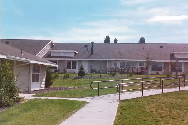 Single-story Aspen Grove Apartments exterior with a walkway, ramp, and grassy courtyard.