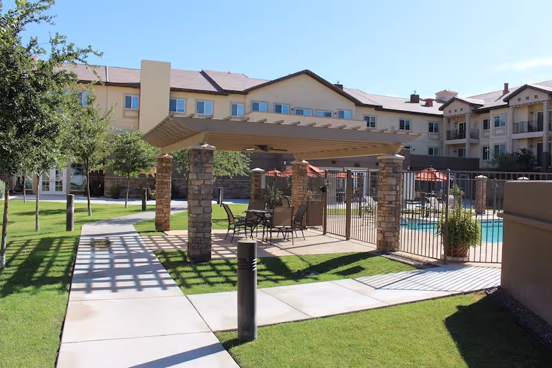 Outdoor pool area at Heritage House Senior Living with a pergola and seating.