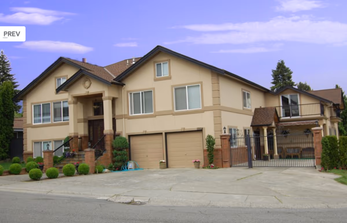 Front view of a beige two-story residential building with a gated driveway.