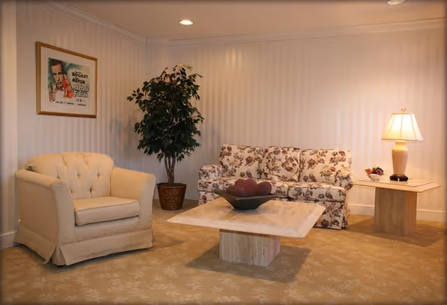 A furnished lounge area with a floral sofa, armchair, coffee table, and lamp.