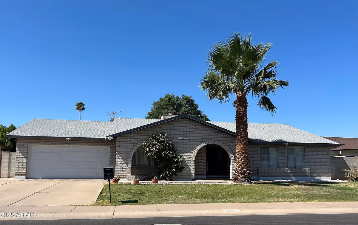 Single-story brick residence with arched entry, attached garage, and palm trees in front yard.