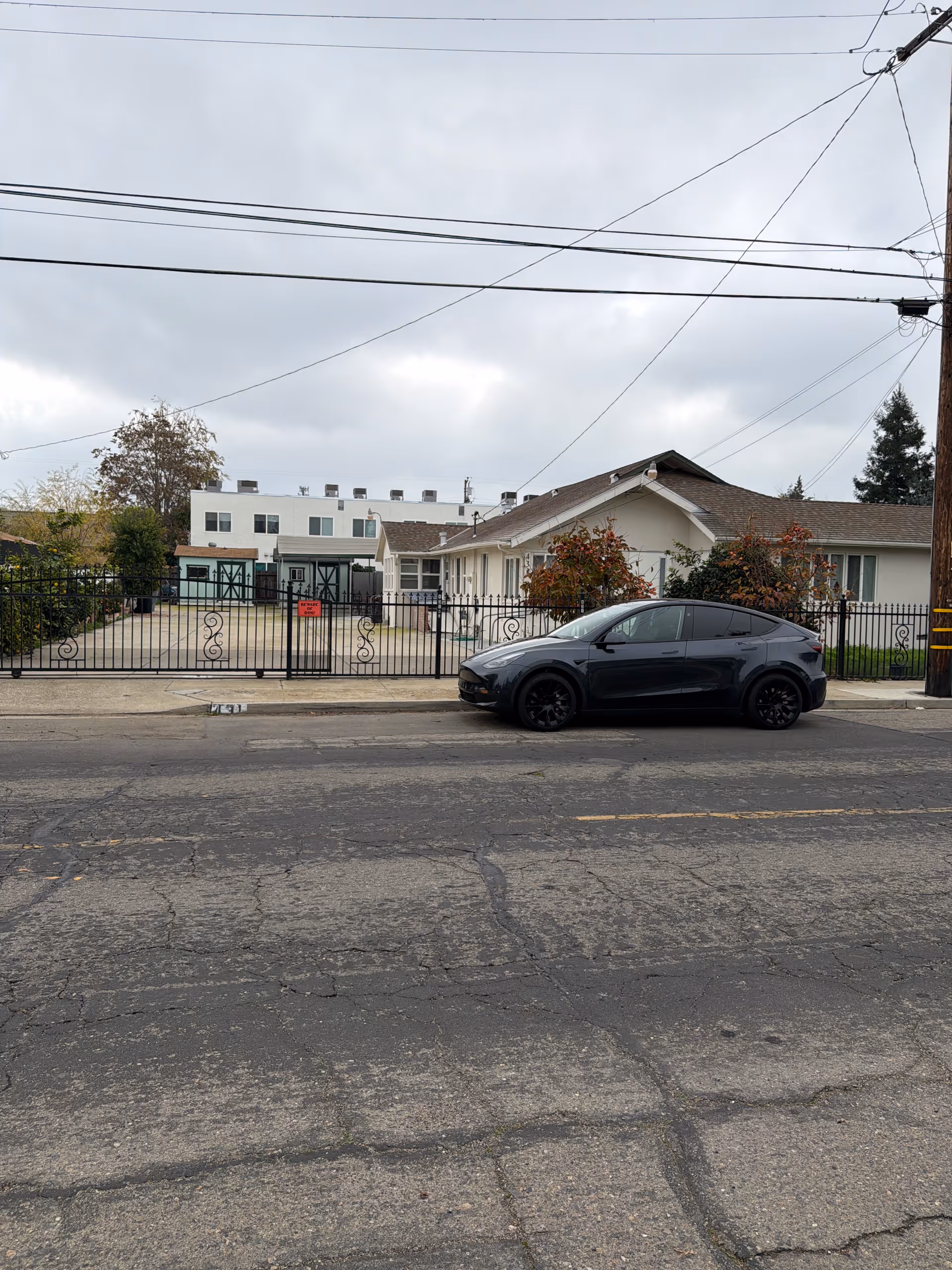 Exterior view of a gated senior care facility along a street with a parked car