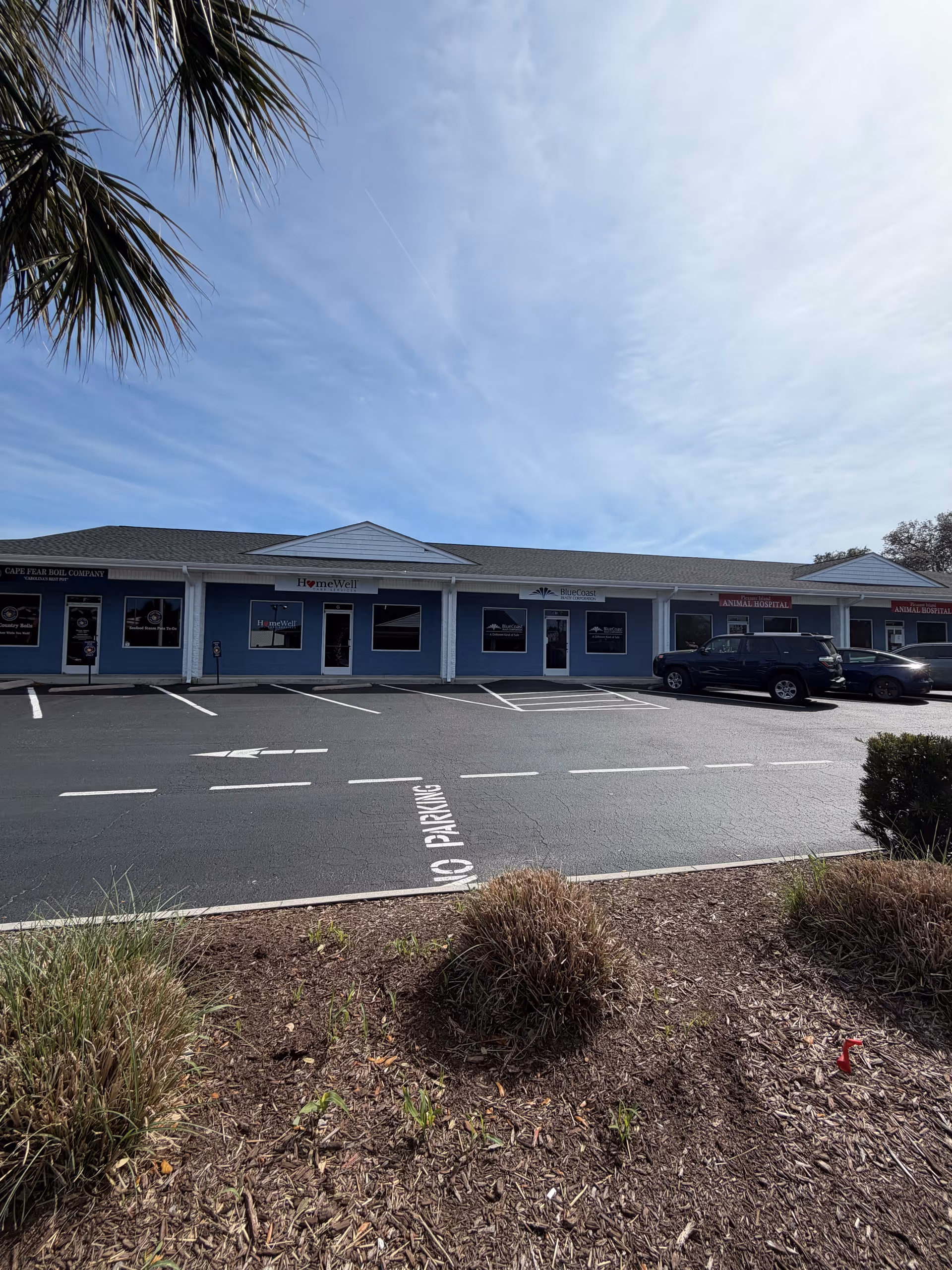 Blue single-story senior care facility with parking lot and landscaping in foreground.