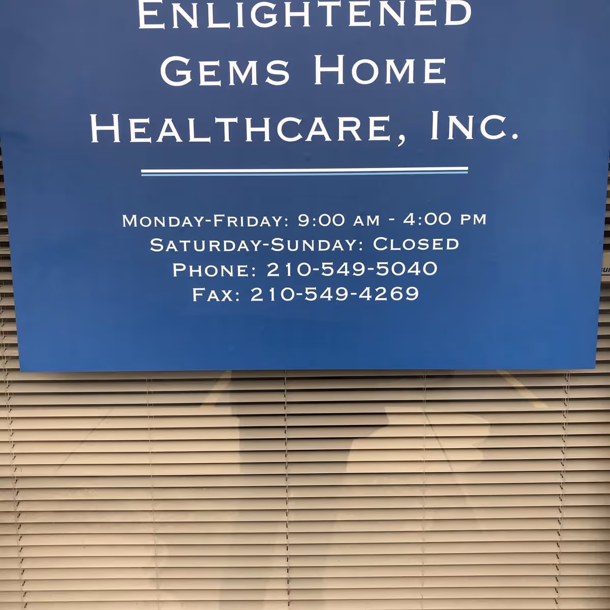 Blue sign reading Enlightened Gems Home Healthcare, Inc. with hours, mounted on building exterior.