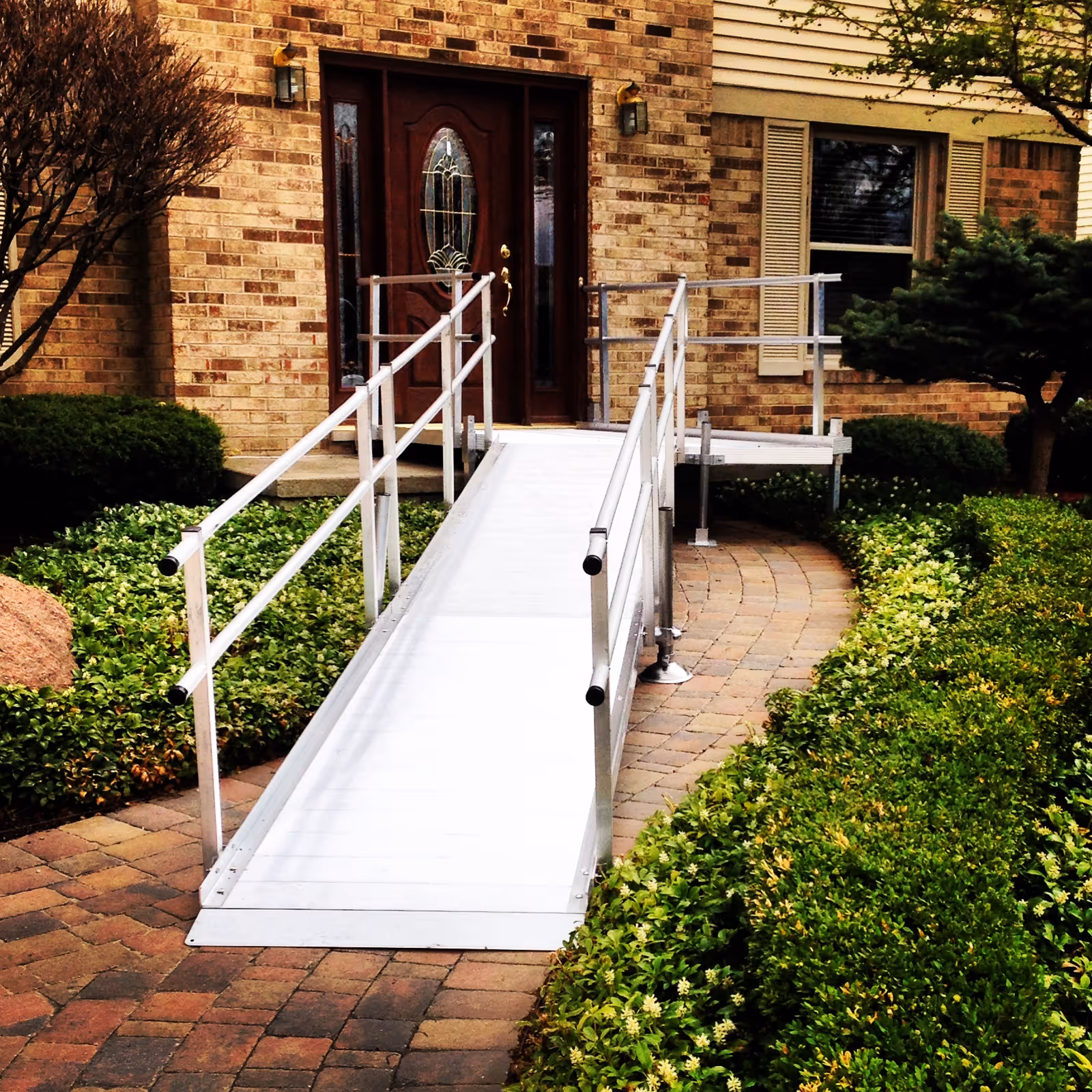 Wheelchair ramp leads to brick building entrance with landscaped surroundings