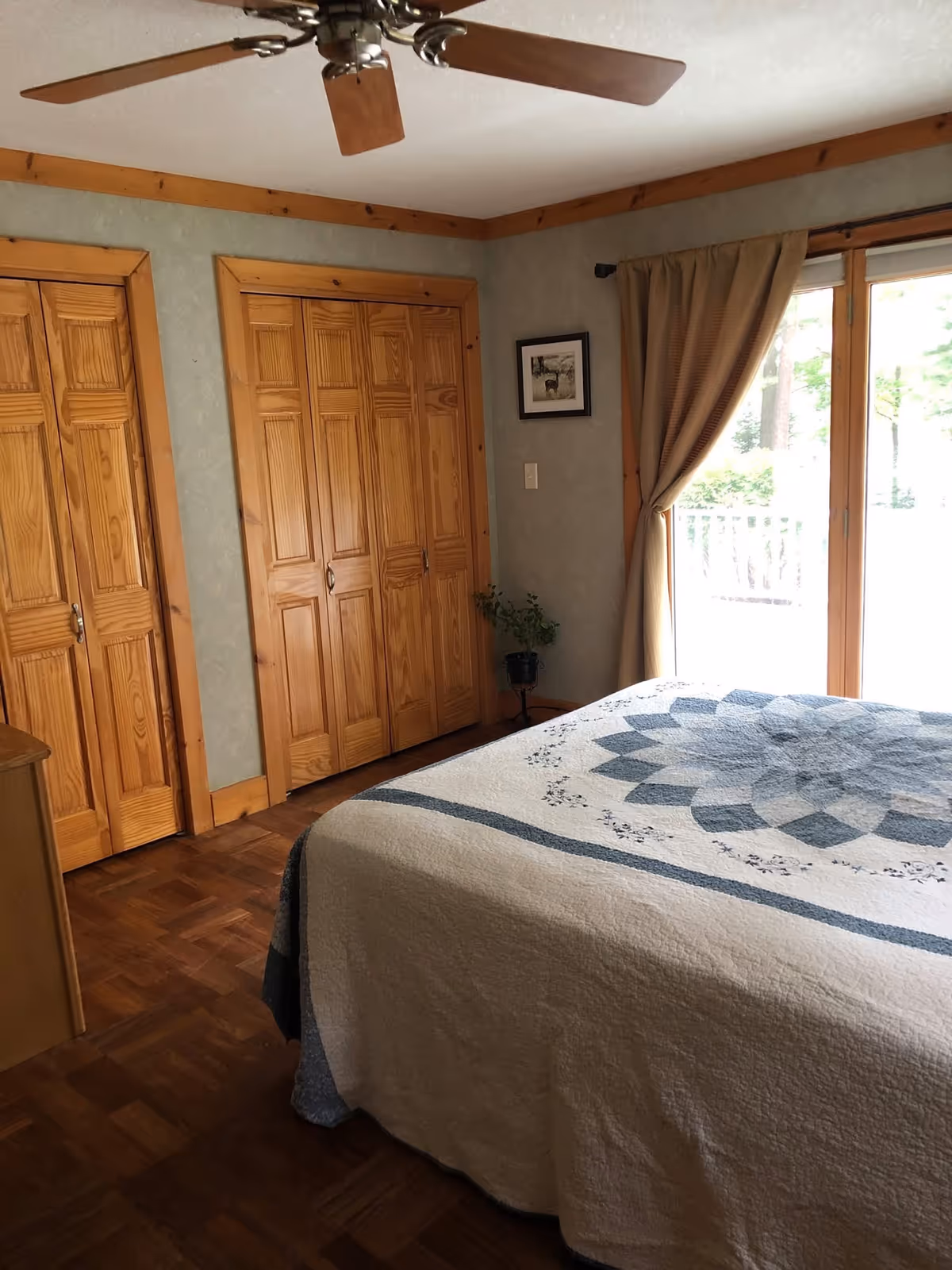 Cozy bedroom with wood closet doors, curtains, ceiling fan, and a neatly made bed.