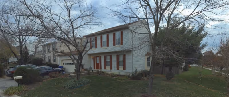 Two-story white building with red shutters, parked cars, and leafless trees in a front yard.