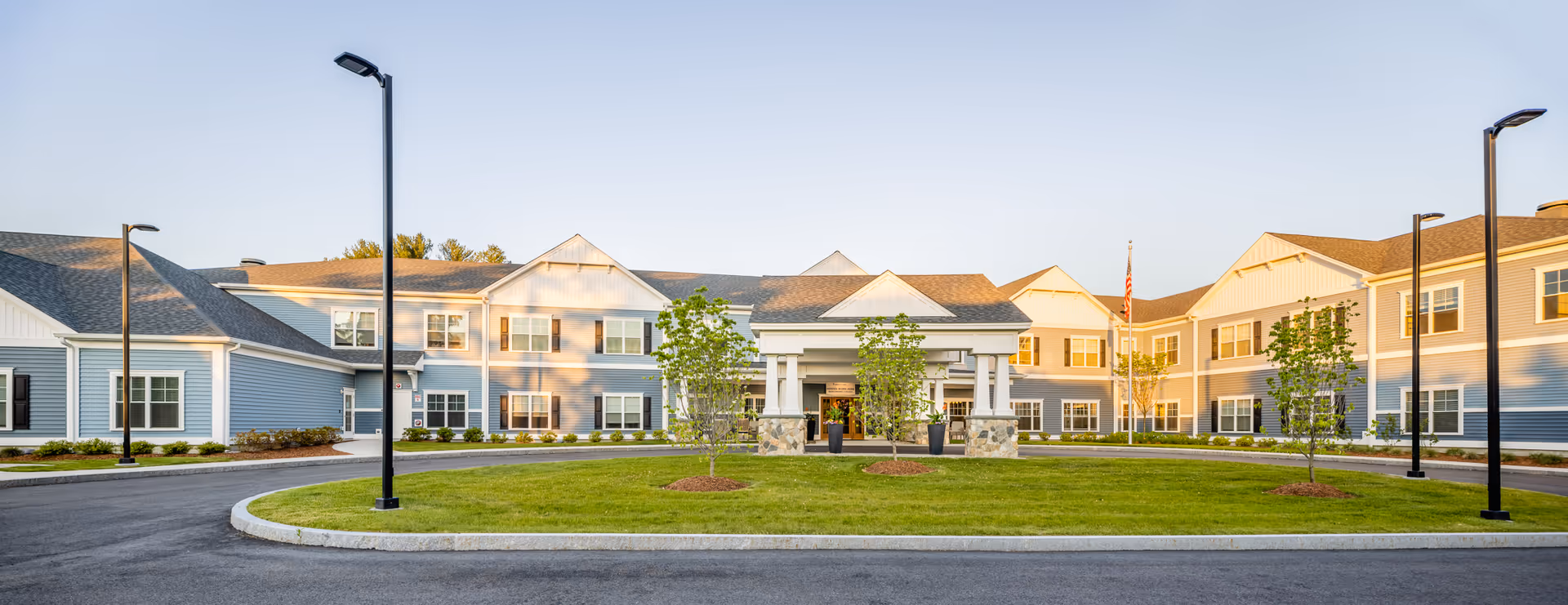 Exterior view of The Branches of Framingham senior living campus with circular driveway and green lawn.