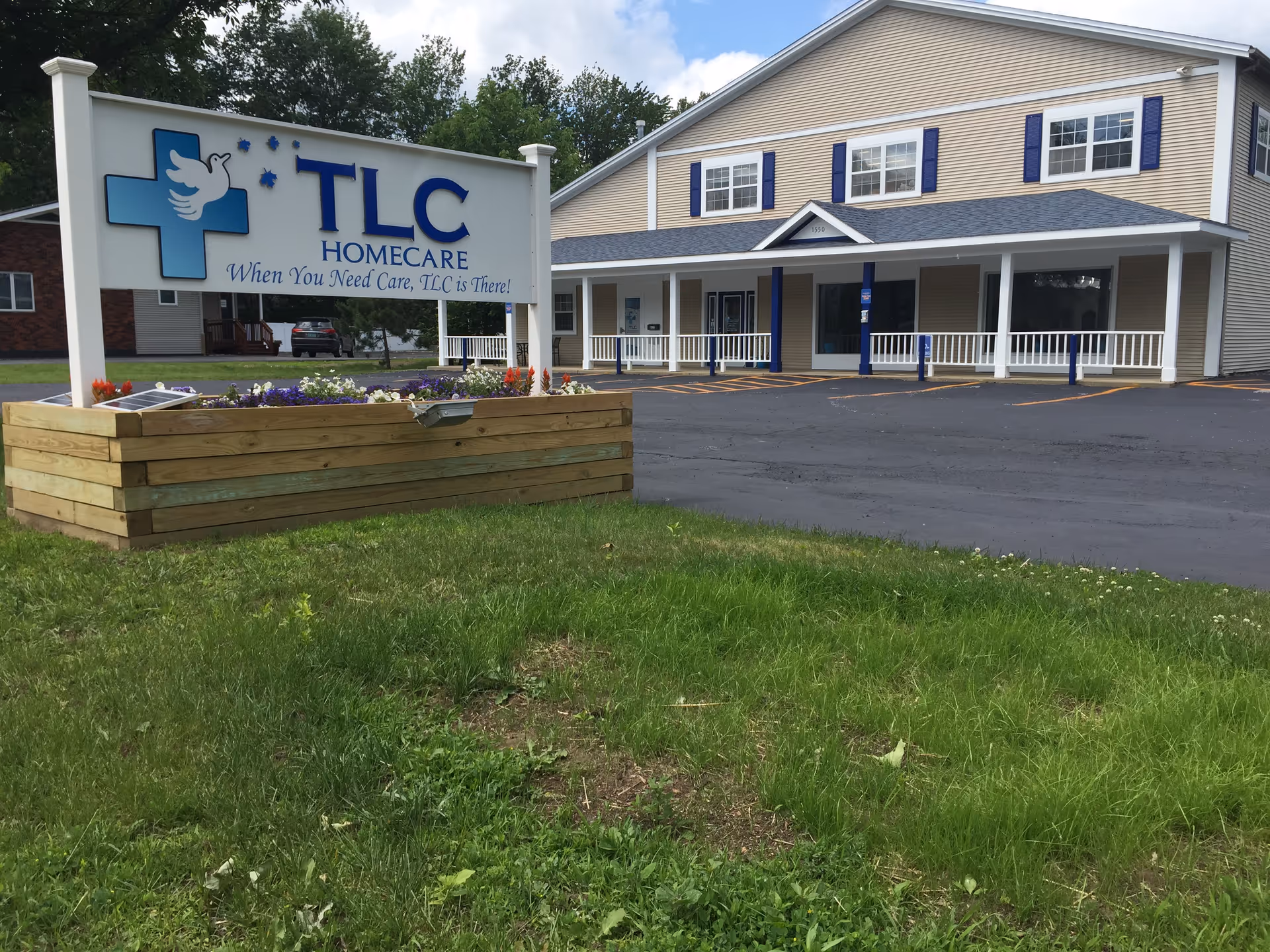 TLC HomeCare facility front with sign, planter box, and a two-story beige building.