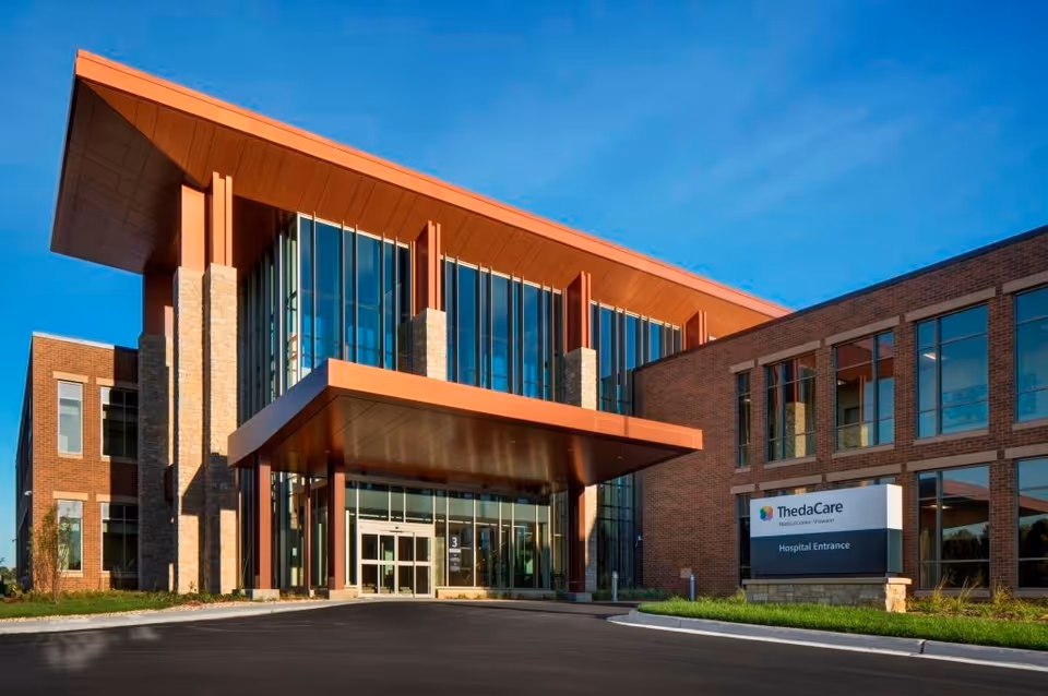 Modern brick building entrance with large glass facade and a covered doorway.