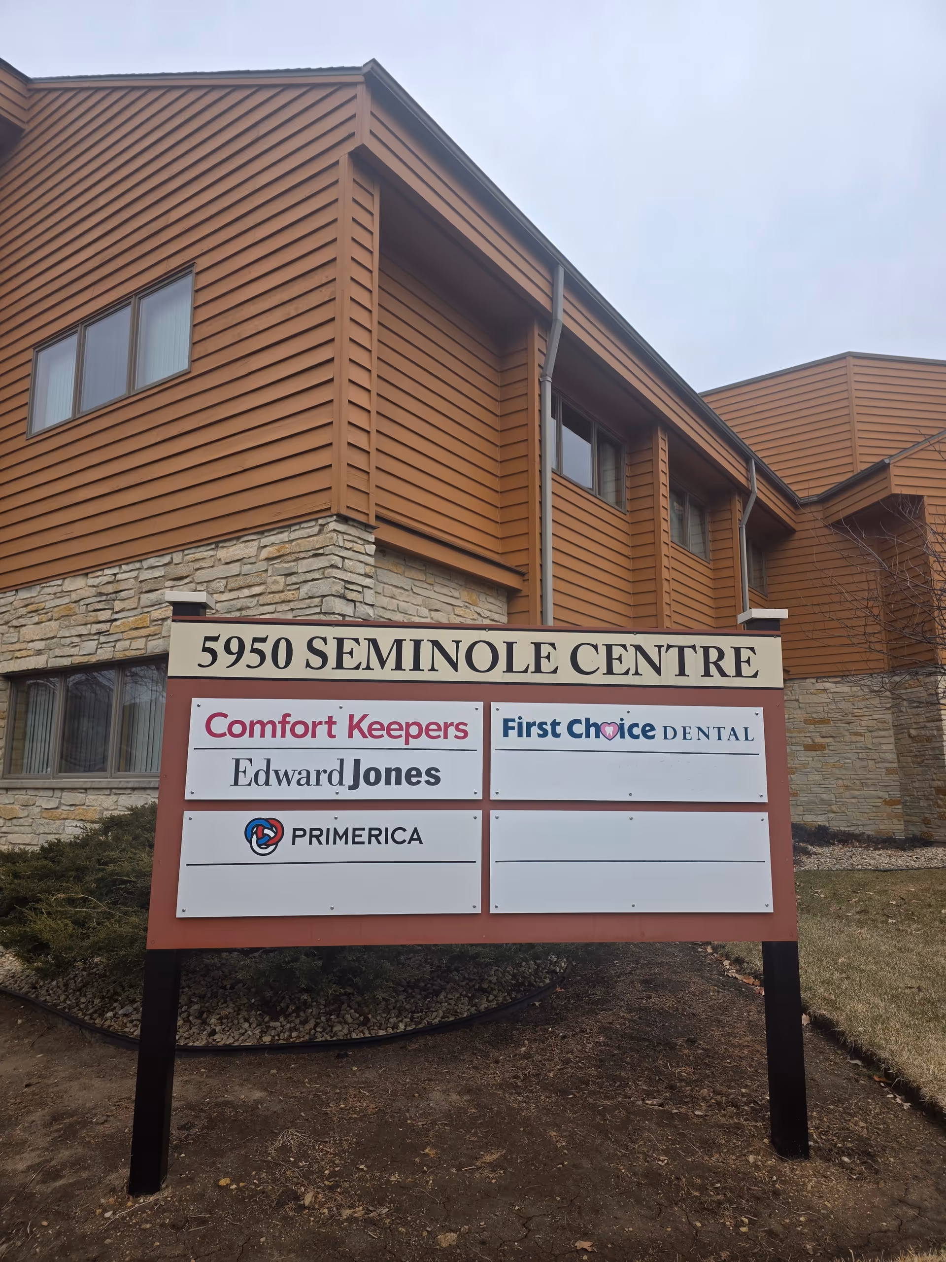 Exterior view of a brown, multi-tenant building with a Comfort Keepers signboard.