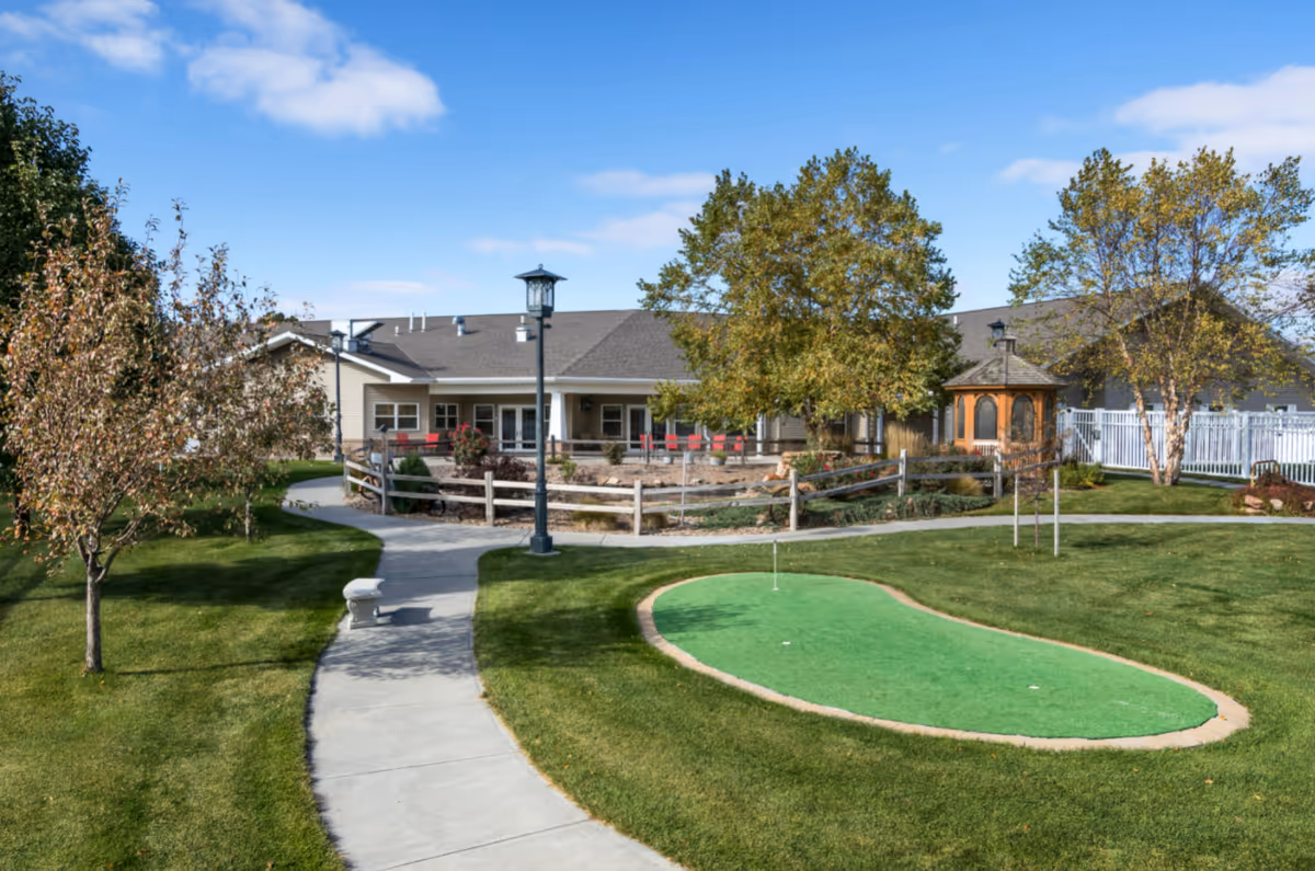 Exterior view of Country Club senior living facility with a green putting area and gazebo.