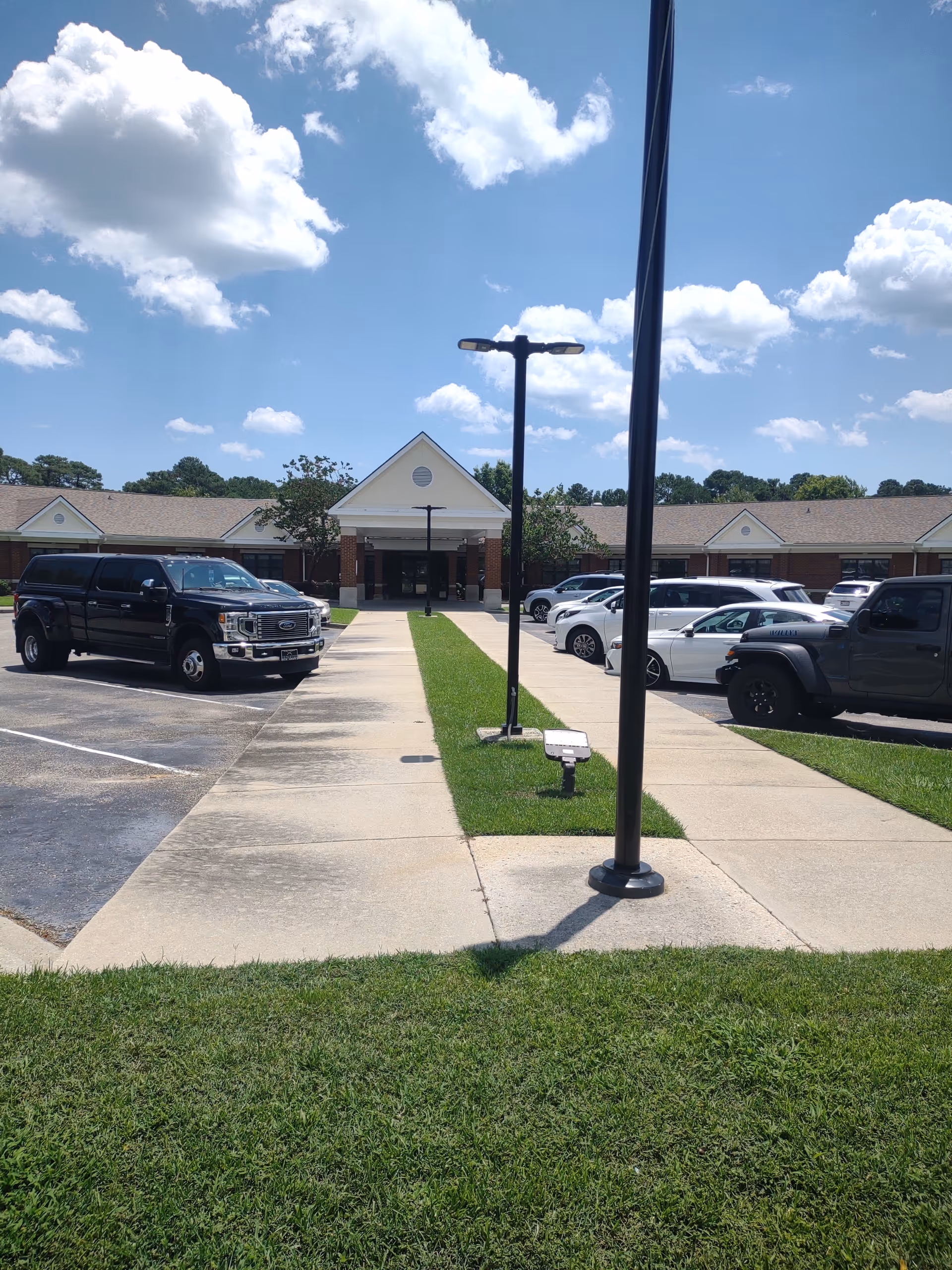Exterior of NHC Healthcare - Garden City showing entrance, parking, and sidewalk.