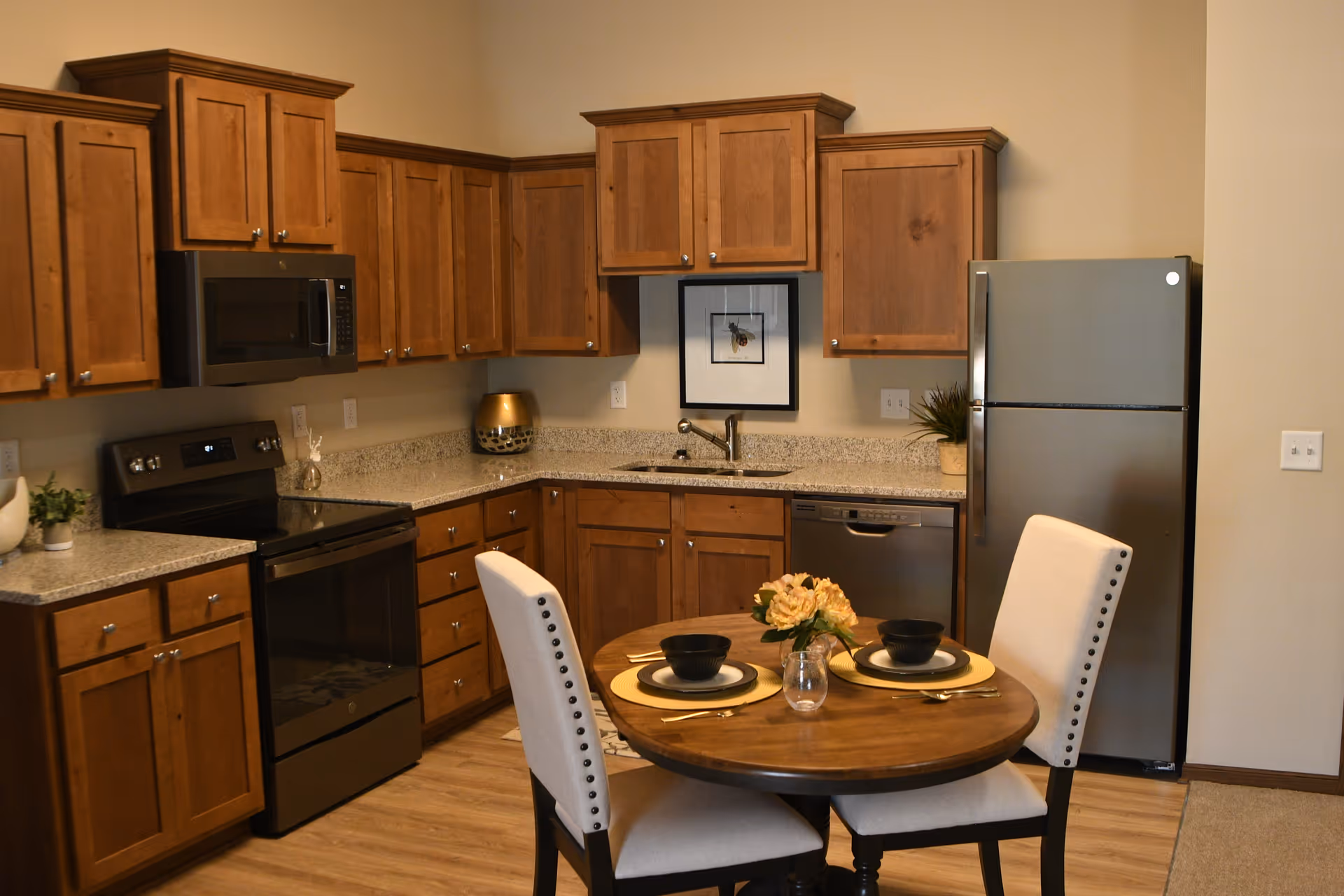 A warm kitchen area with wooden cabinets, stainless appliances, and a small round dining table.