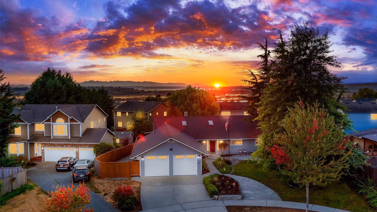 A row of suburban houses at sunset with well-kept yards and a curved driveway, front view.