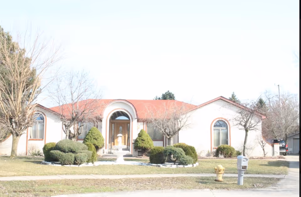 Front view of a senior living facility with arched entry and landscaped yard
