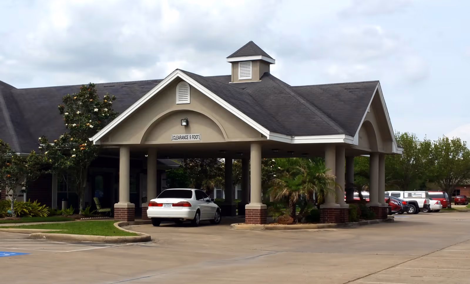 Front entrance of Park Manor of South Belt with porte-cochere and parked cars.