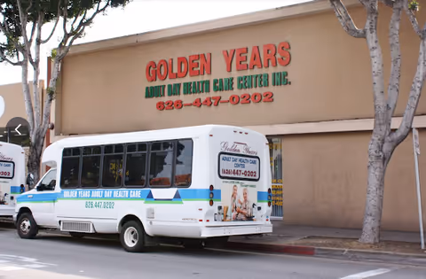 White bus parked in front of a beige building labeled Golden Years Adult Day Health Care.