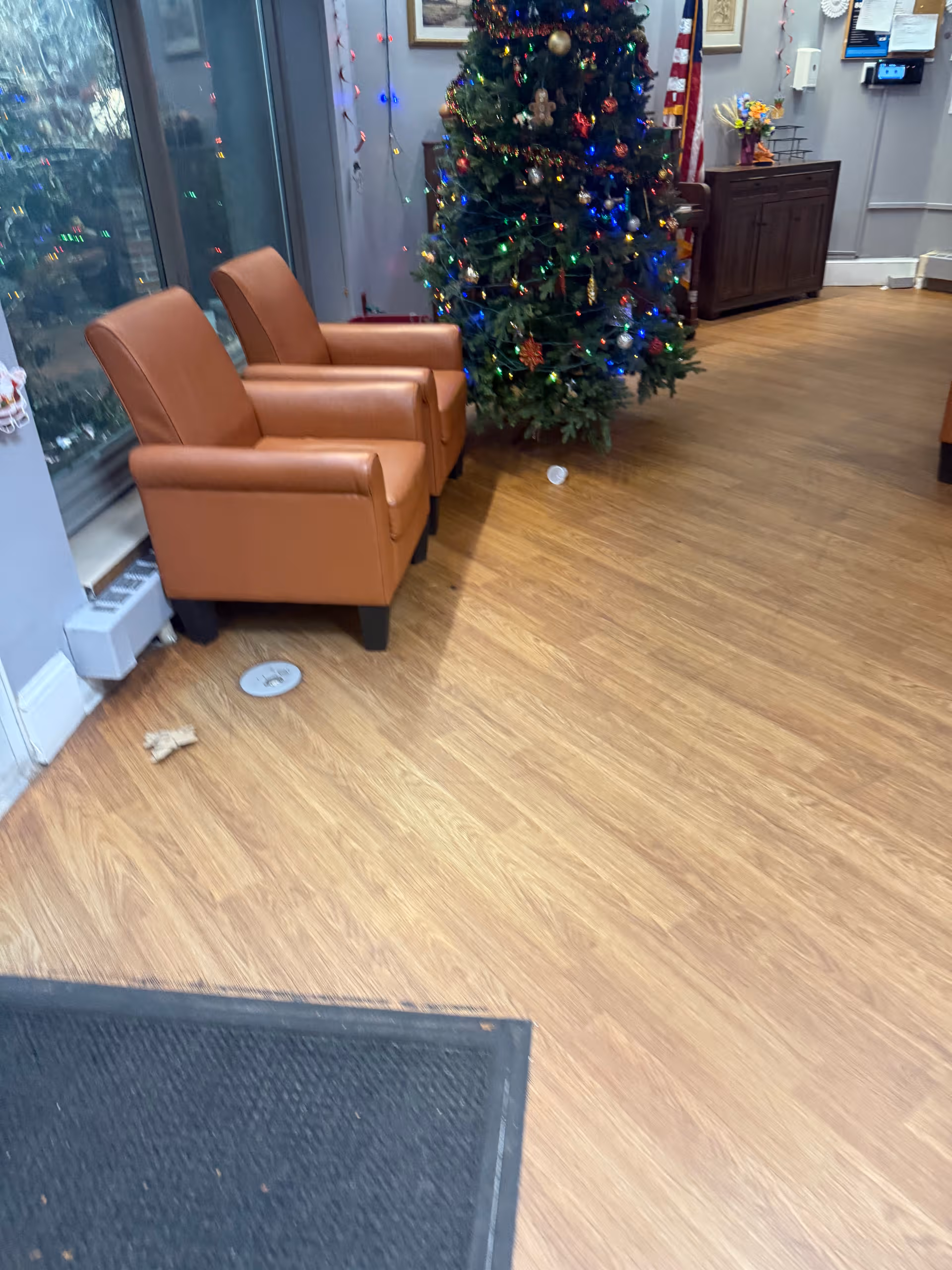 Interior lobby seating area with two brown chairs and a decorated Christmas tree