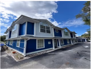 Blue two-story senior living building exterior with white trim and pavement.