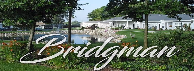 Exterior view of Woodland Terrace with landscaped lawn, pond, and a Bridgman sign in foreground.