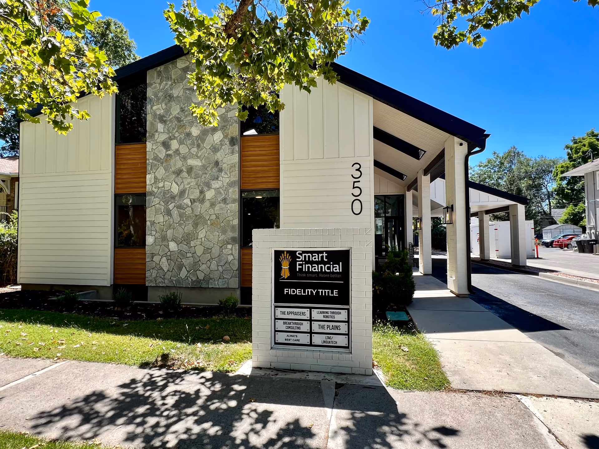 Modern beige building exterior with stone accents and a freestanding sign in front.