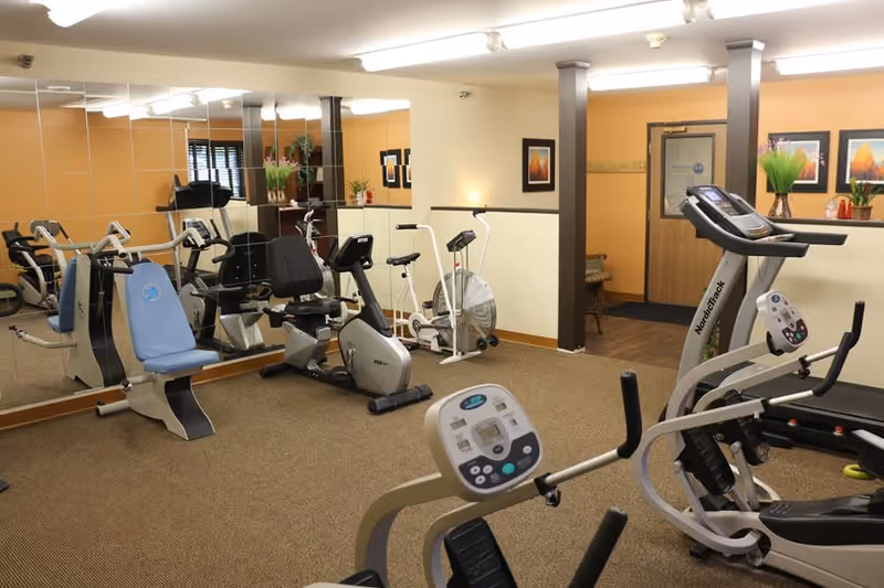 Interior fitness center with treadmills, stationary bikes, and mirrored walls.