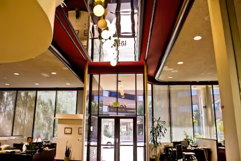 Bright lobby area with glass doors, tall windows, and seating under pendant lights.