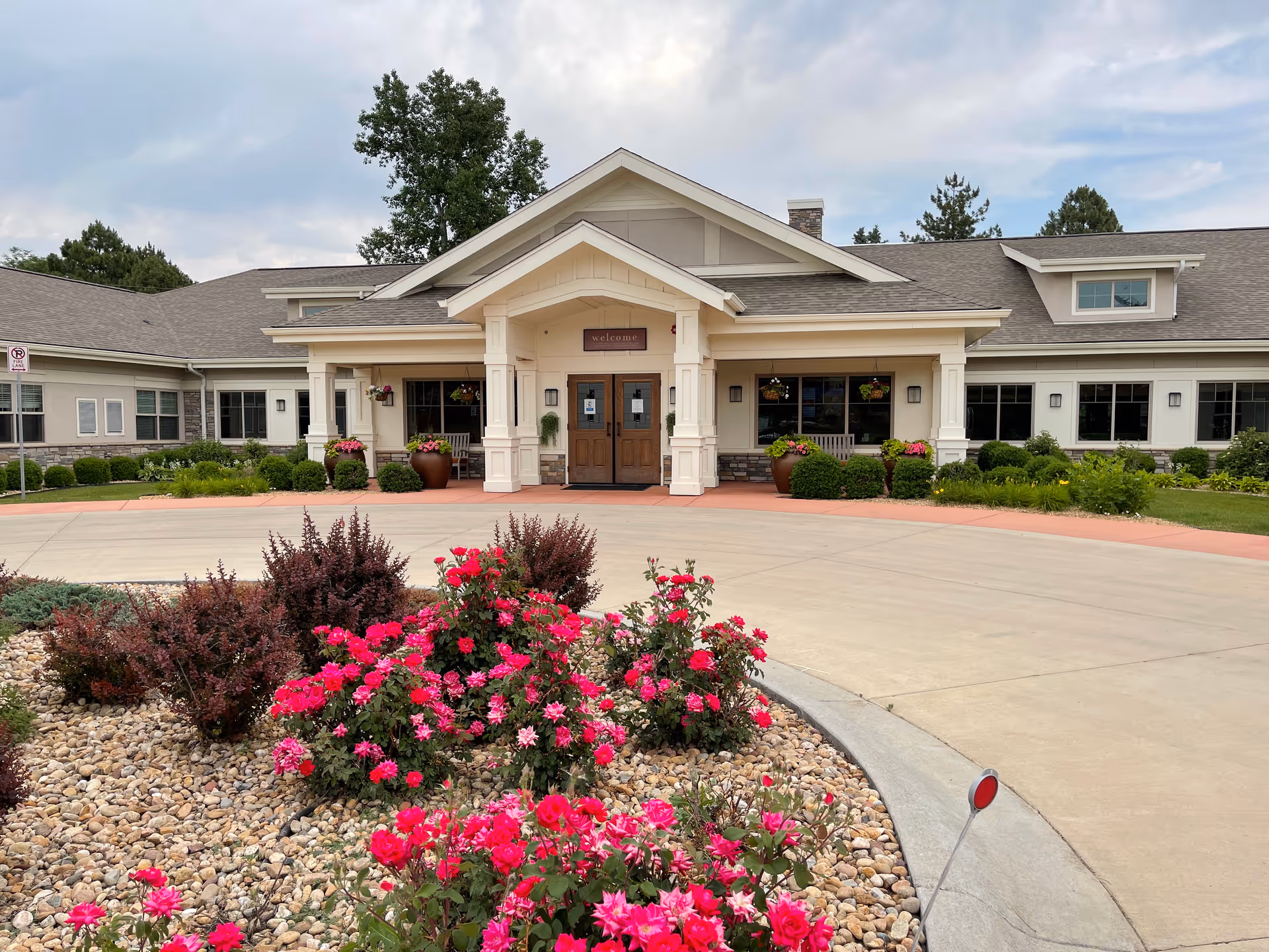 Front view of Lakewood Memory Care facility with entryway, columns, and landscaped flower beds.