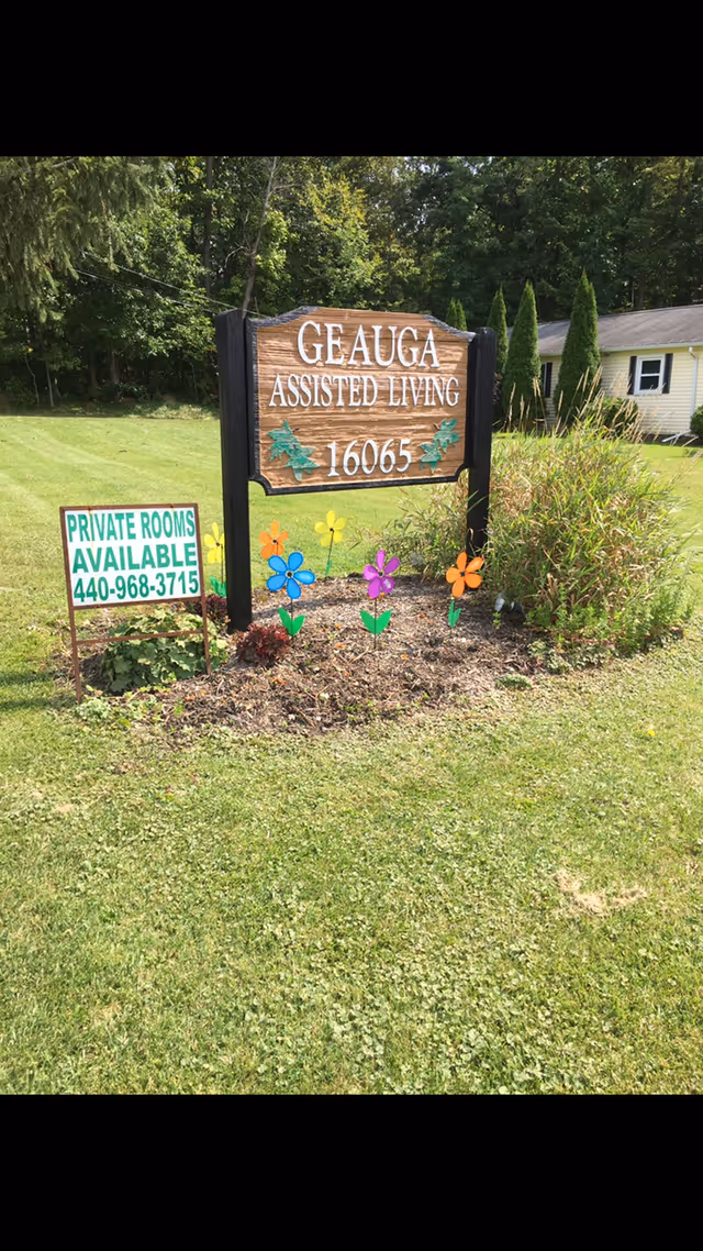 Geauga Assisted Living sign posted by a green lawn with colorful flowers.