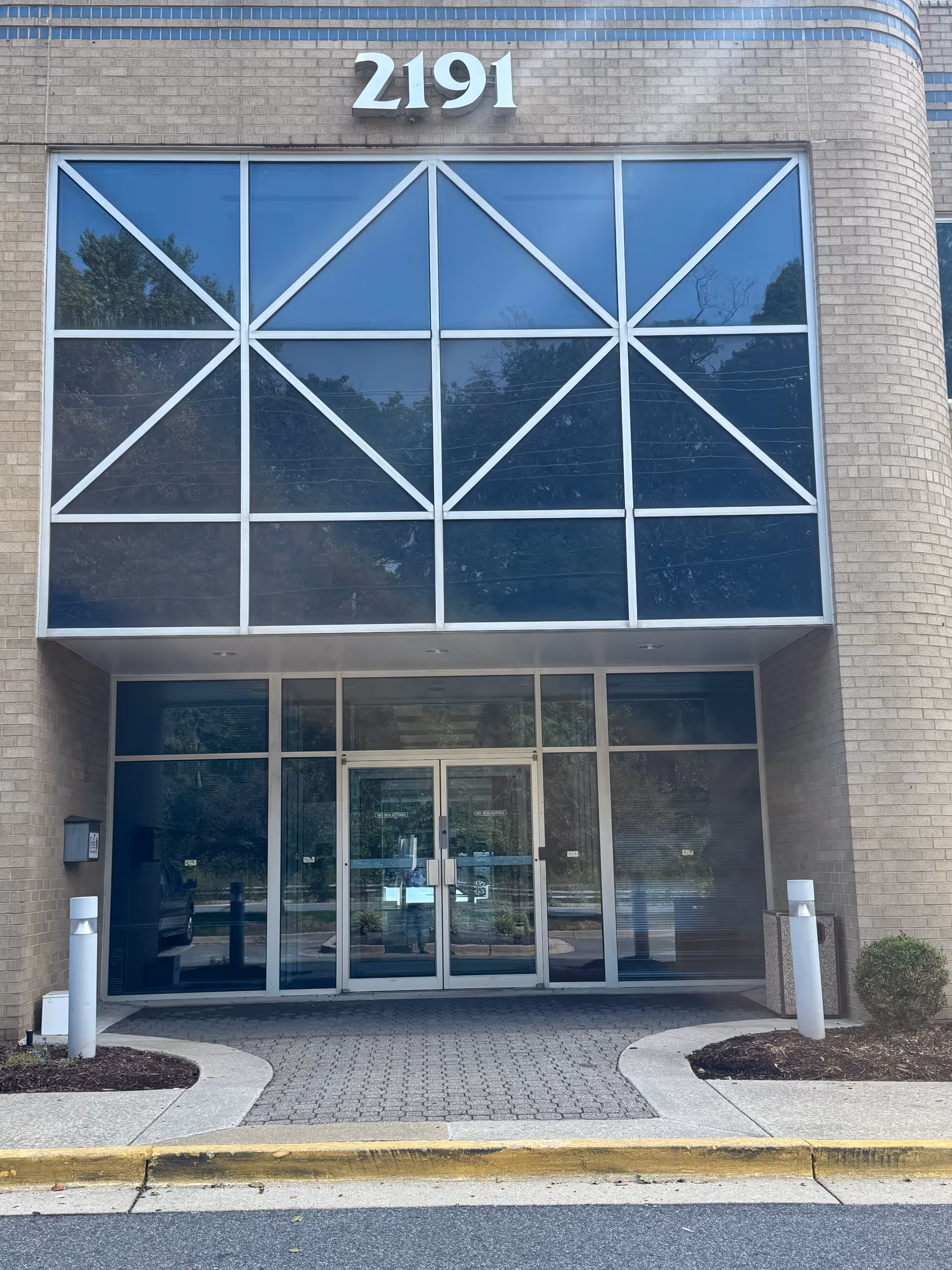 Front entrance of a brick building with large glass doors, address 2191.