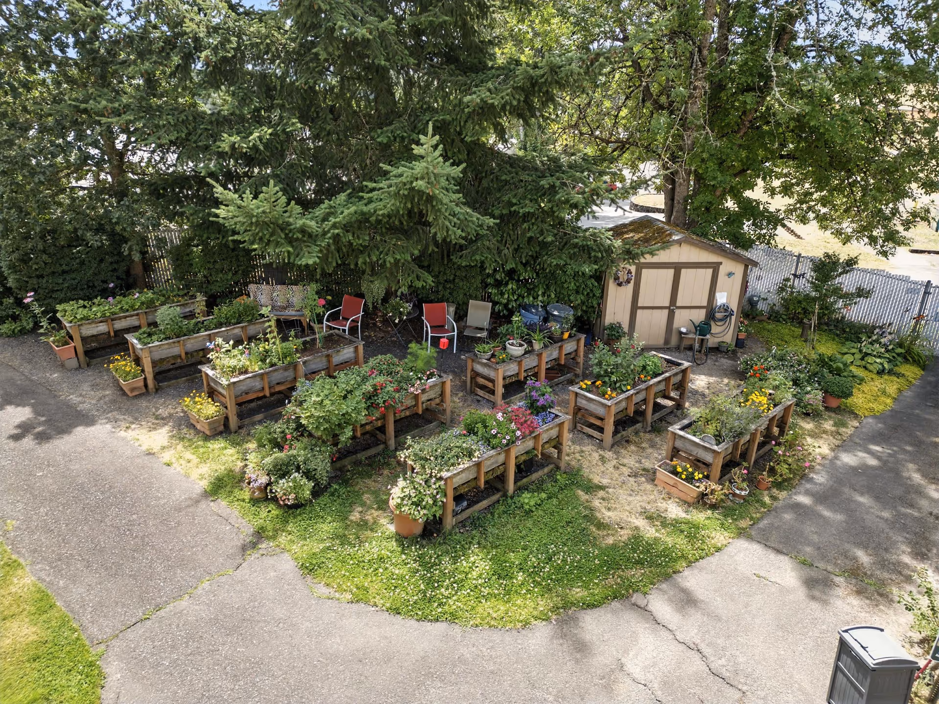 Outdoor courtyard garden with raised planters, benches, and a small shed.