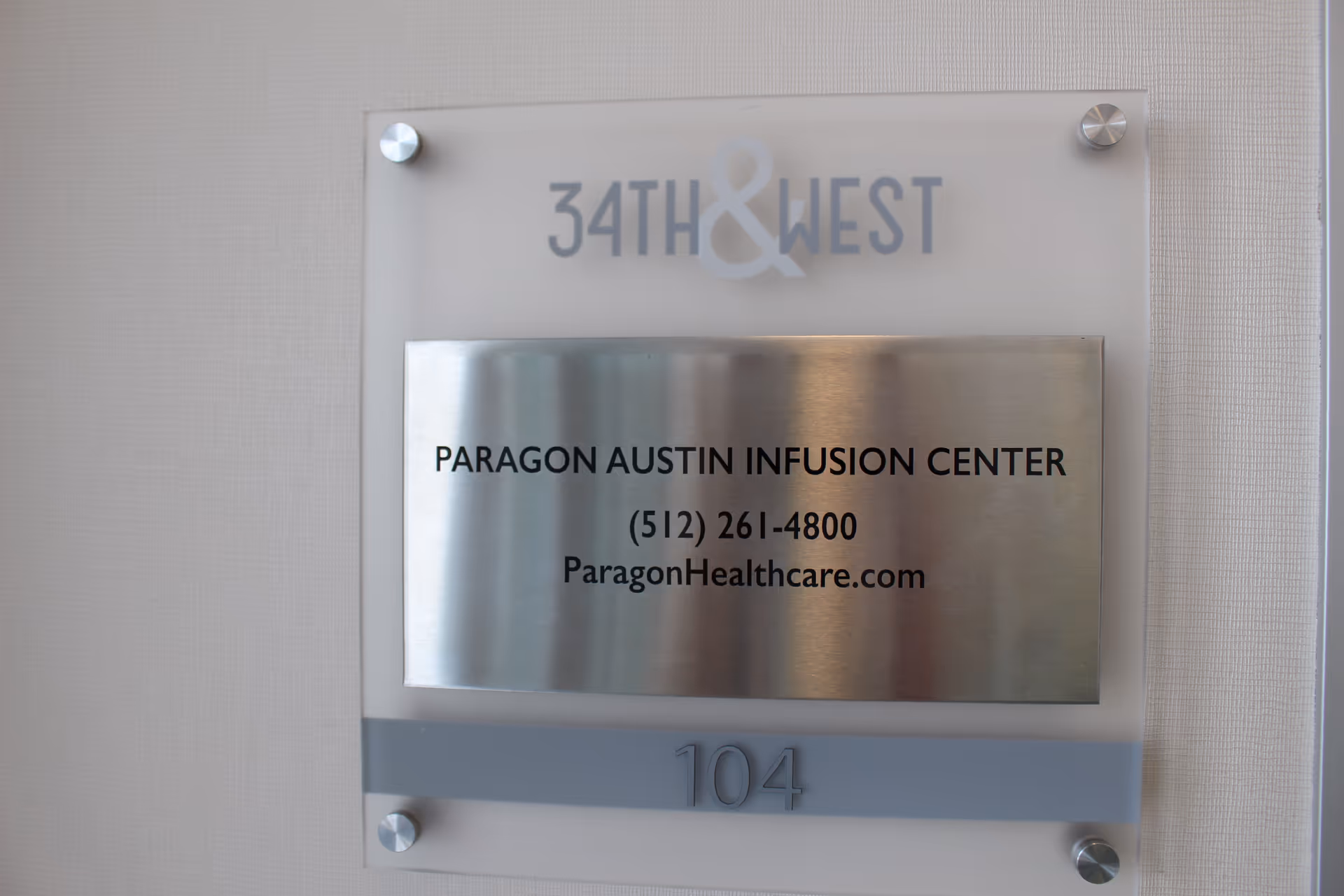 Metal wall plaque reads Paragon Austin Infusion Center, suite 104, 34th & West.