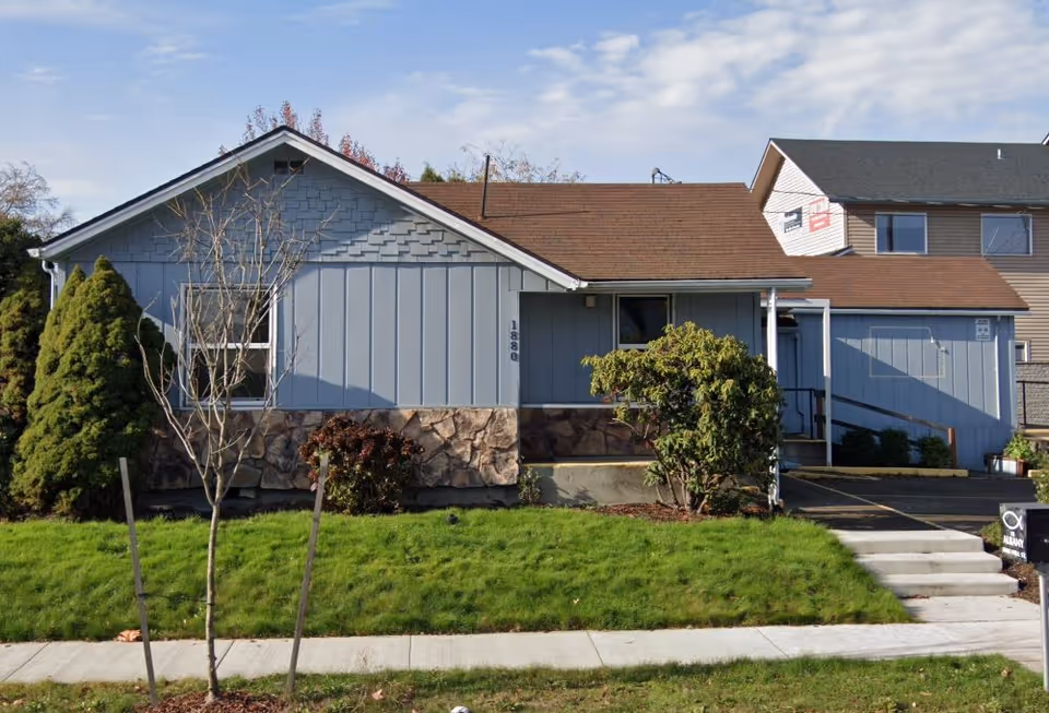 Front view of a blue single-story building with stone base and walkway