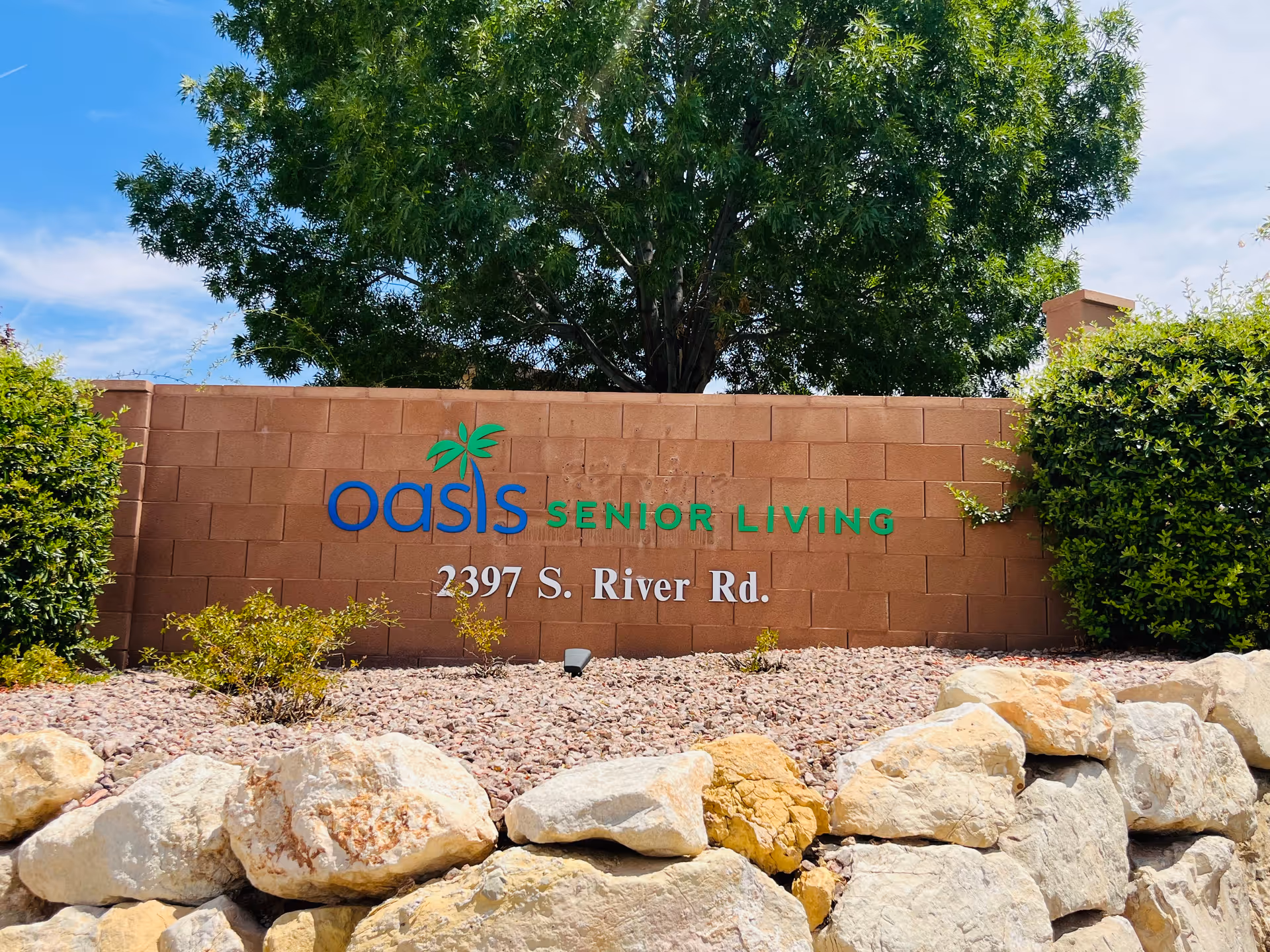 Brick wall sign for Oasis Senior Living with landscaping in front.