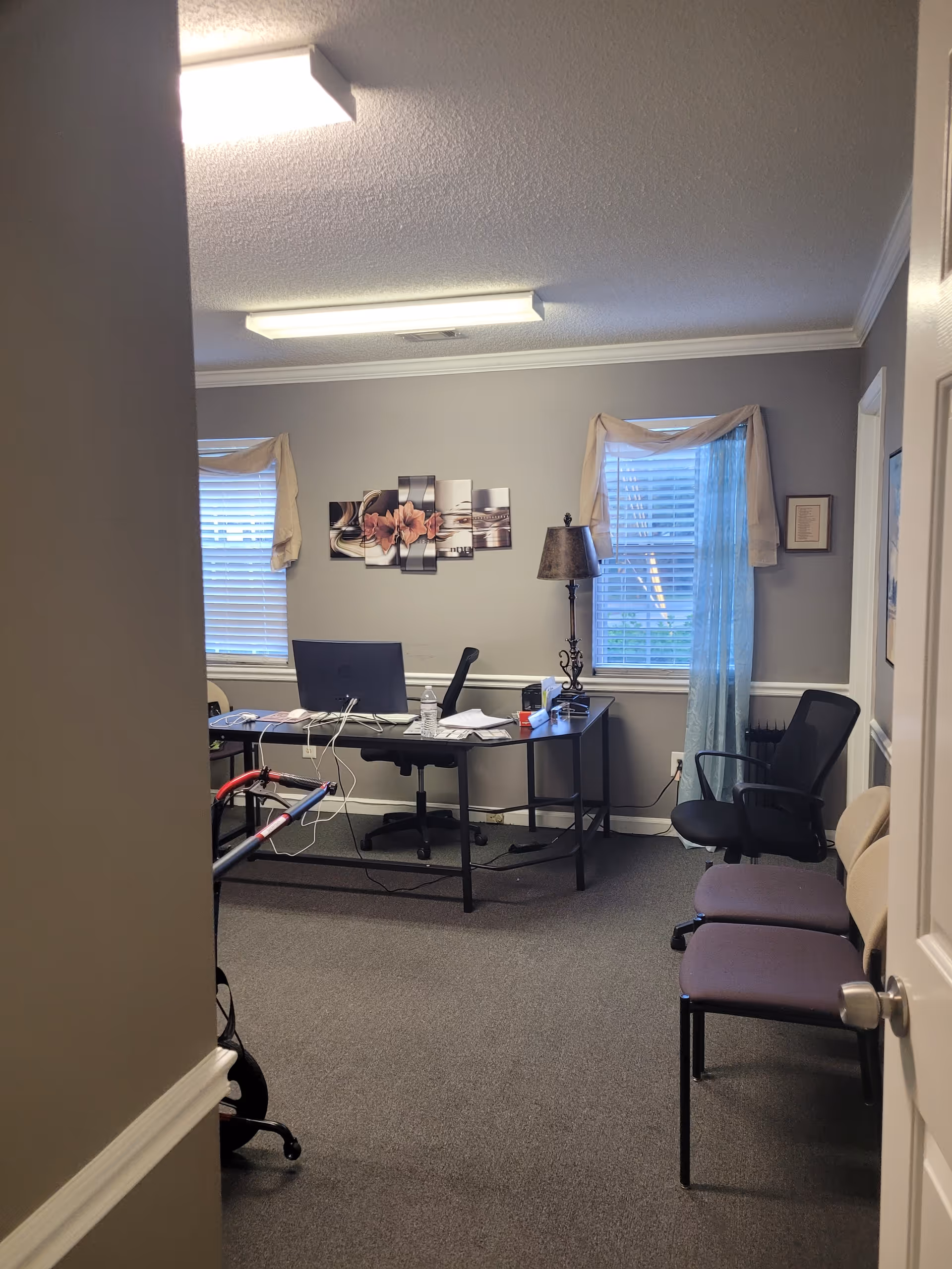 Small office in a senior living facility with a desk, laptop, and chairs.