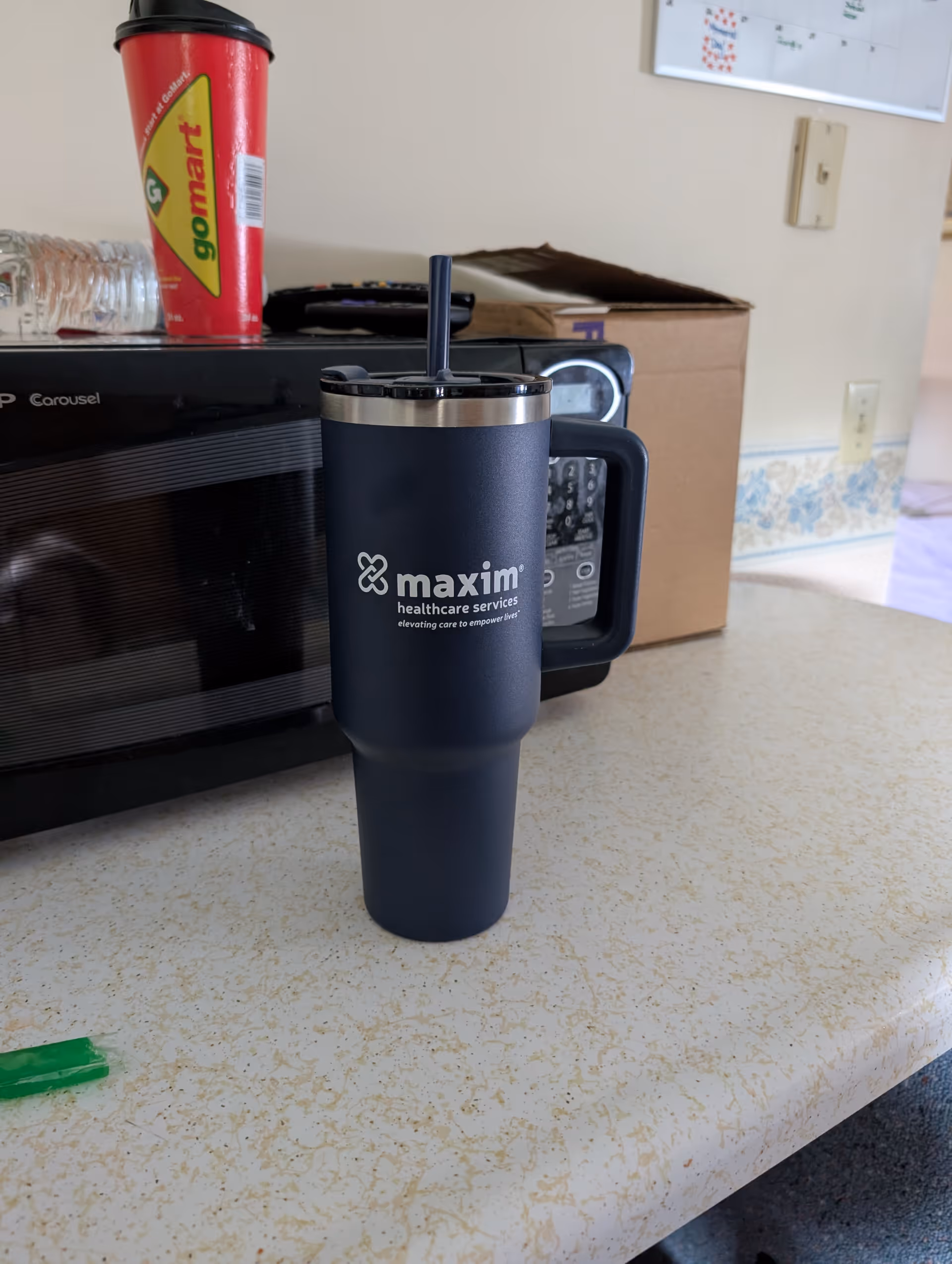 Dark blue Maxim tumbler on a kitchen counter near a microwave.