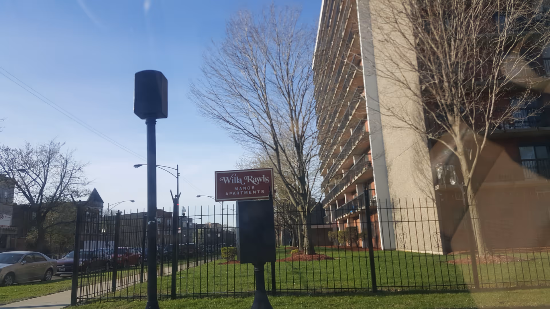 Exterior view of Willa Rawls Manor Apartments with a tall sign and multi-story building.