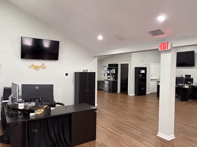 Reception area with desks, computers, cabinets, and wall TV