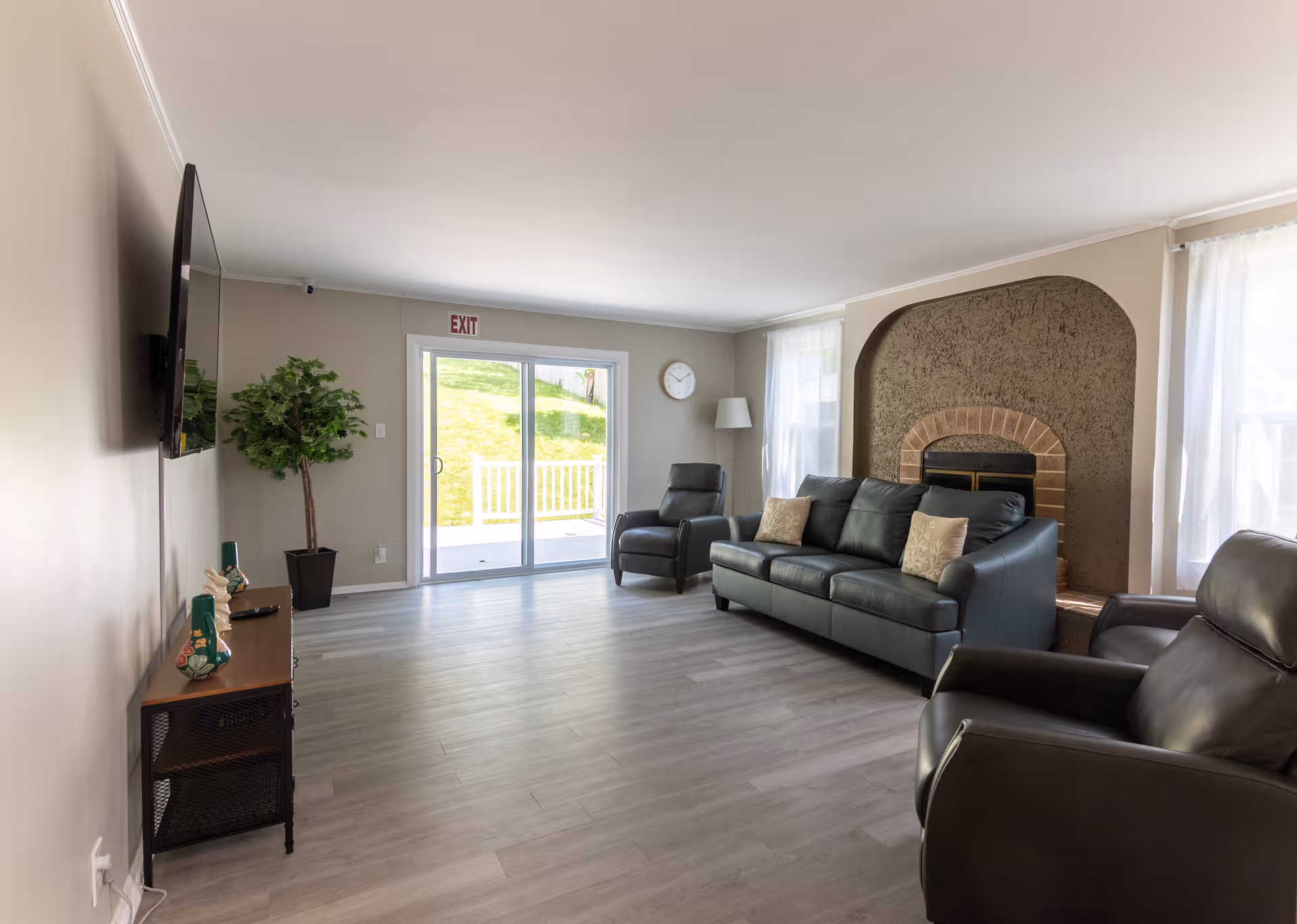 Spacious living room with leather sofas, a brick fireplace, and sliding glass doors.