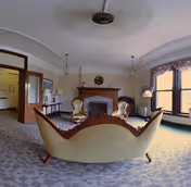 Vintage living room with a curved sofa and two armchairs facing a fireplace under a decorative ceiling medallion.